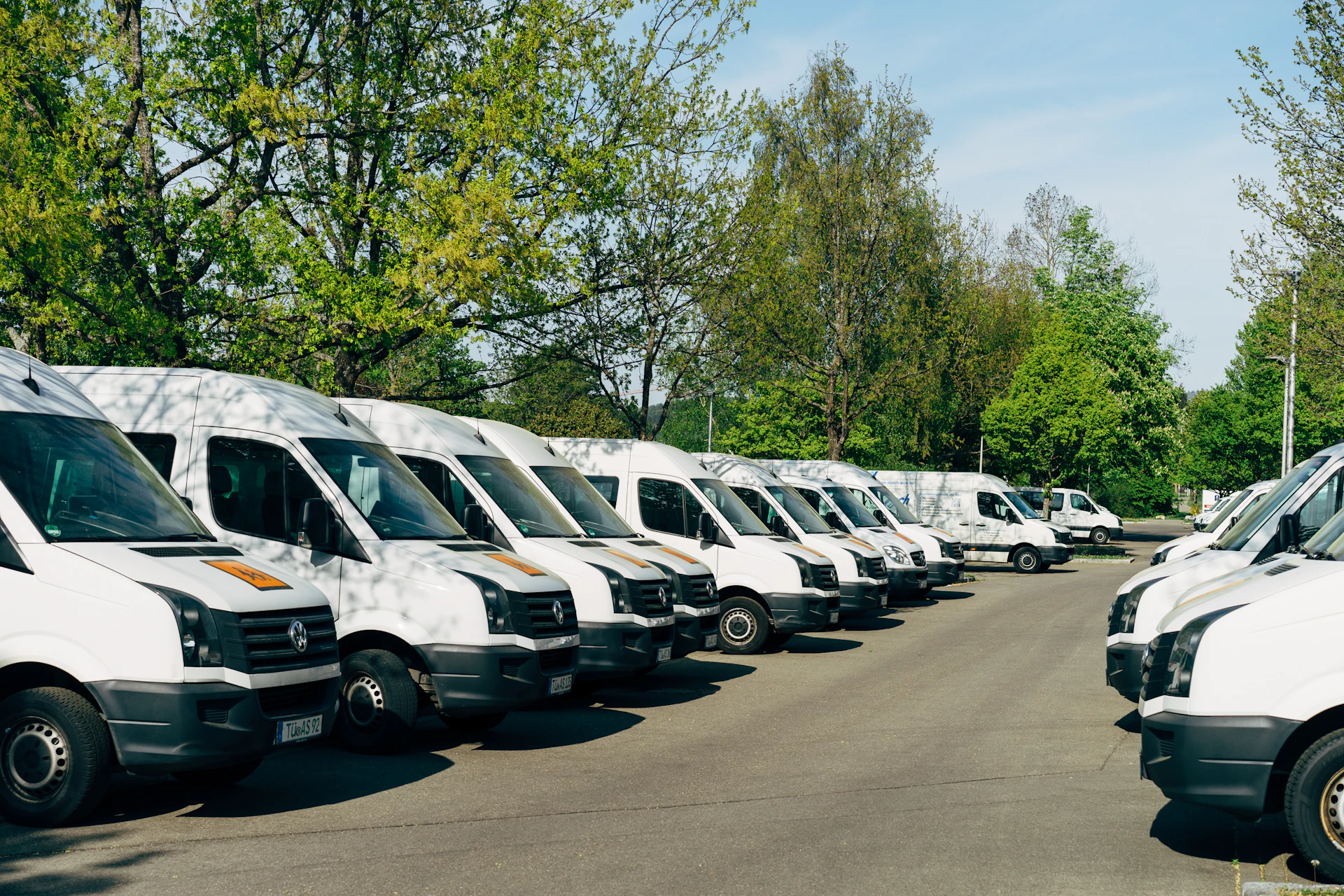 A fleet of matte grey delivery trucks lined up outside a modern distribution center on a clear day